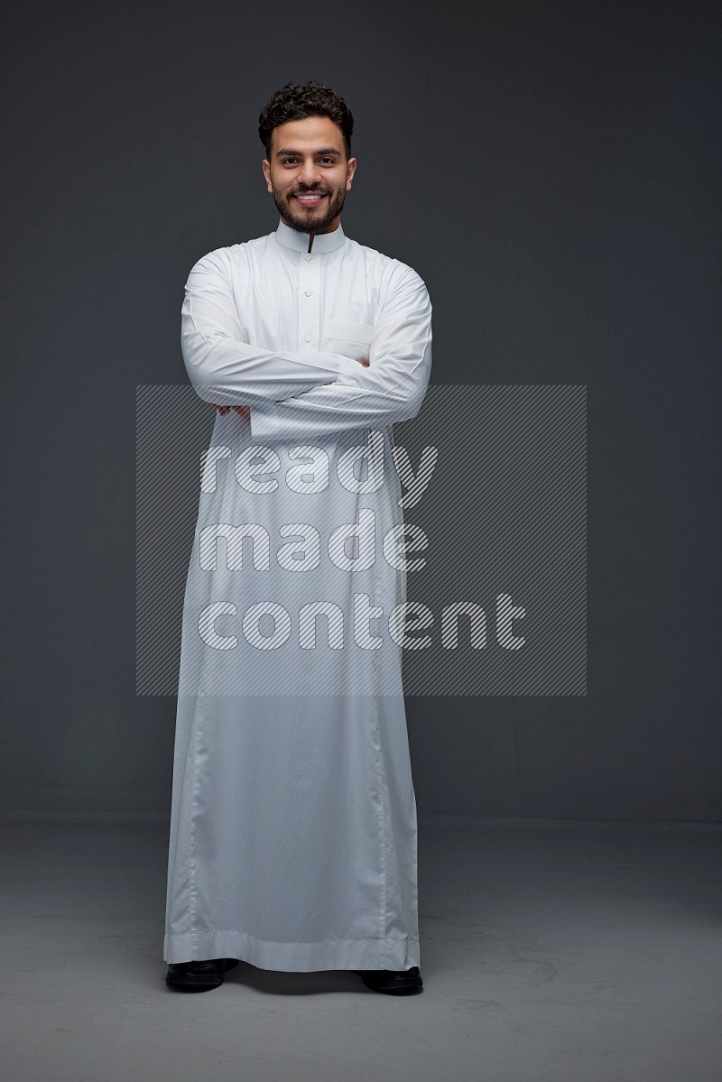 A Saudi man wearing Thobe standing and making different poses eye level on a gray background