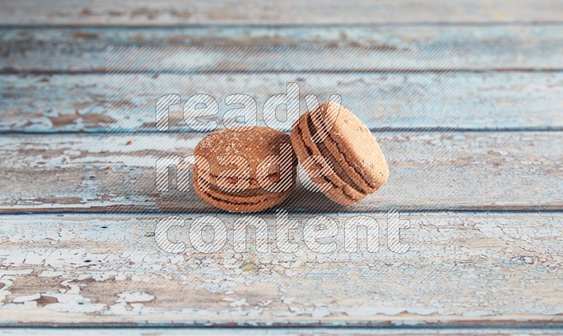 45º Shot of two Brown Hazelnuts macarons on light blue wooden background