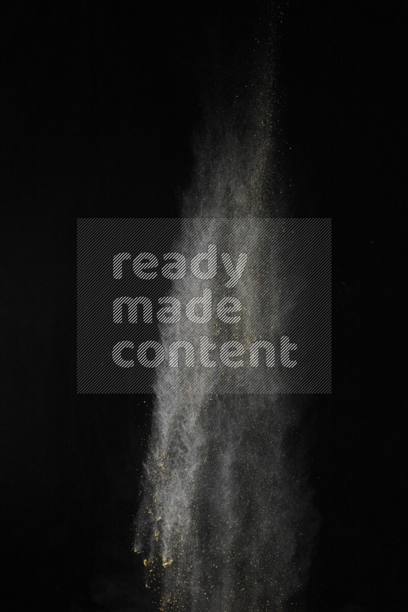 A side view of yellow powder explosion on black background
