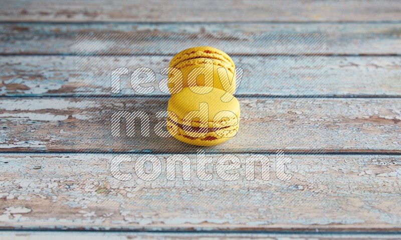 45º Shot of two Yellow Lemon macarons on light blue wooden background