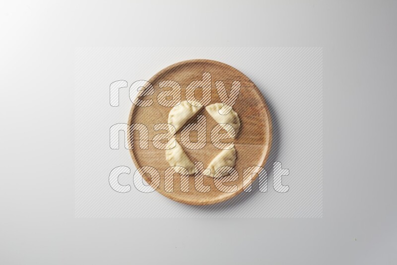 Four Sambosas on a wooden round plate on a white background