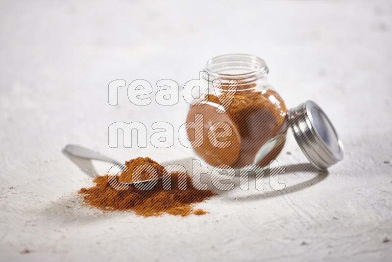 A glass jar full of ground paprika powder on white background