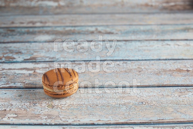 45º Shot of light brown Almond Cream macaron on light blue wooden background