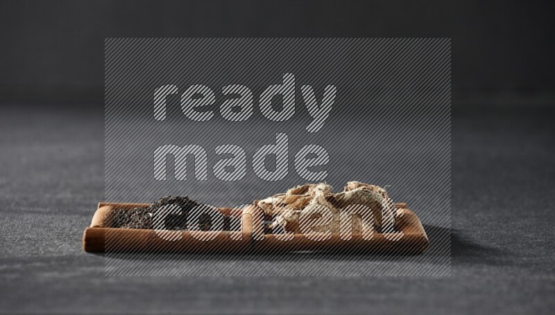 مربعان من أعواد القرفة ممتلئان بالزنجبيل المجفف والشاي الأسود علي خلفية سوداء