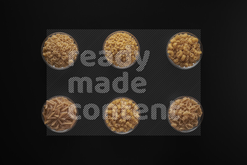 أنواع مختلفة من المعكرونة في أوعية زجاجية علي خلفية سوداء