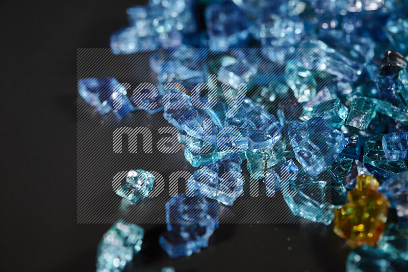 Transparent blue fragments of glass scattered on a black background