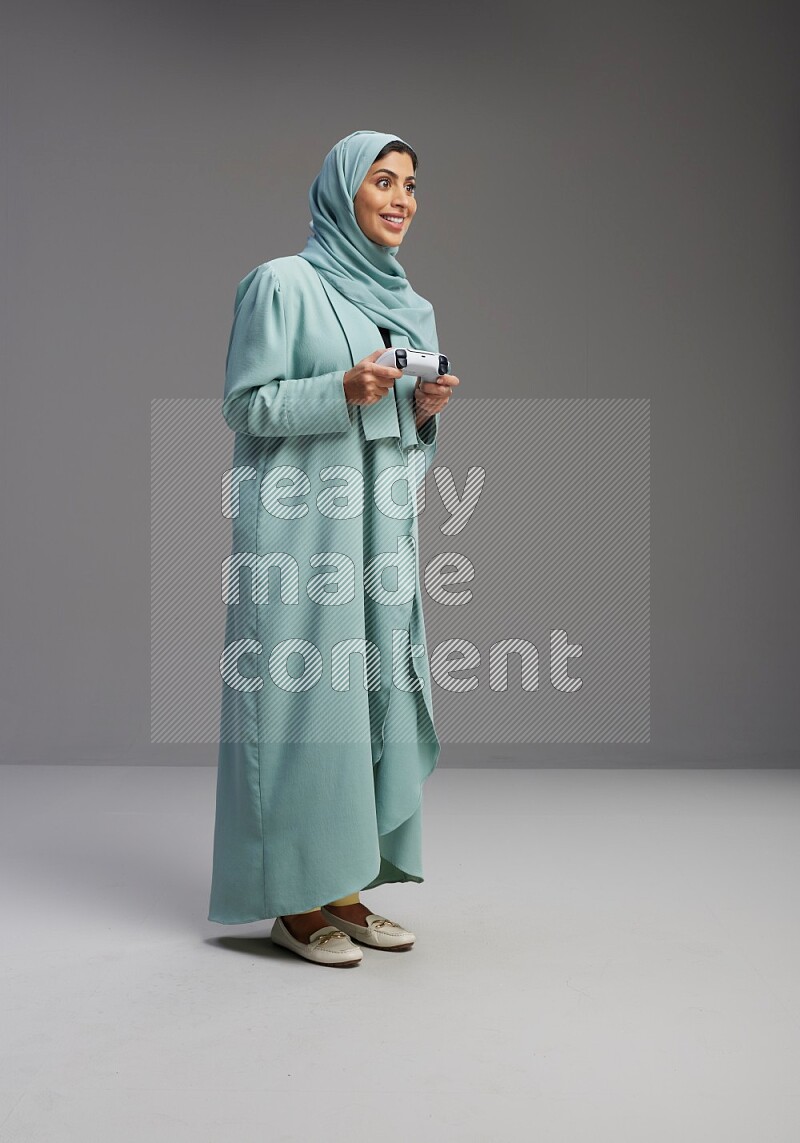 Saudi Woman wearing Abaya standing Playing Games on Gray background
