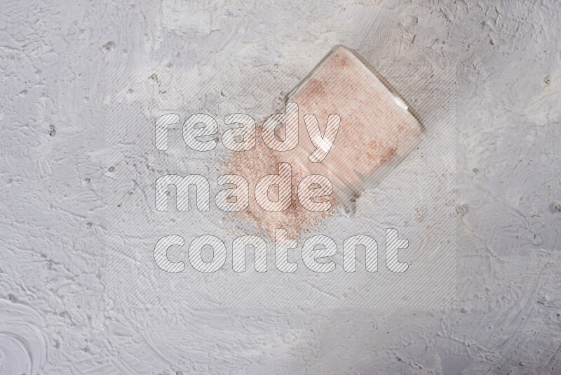 A glass jar full of fine himalayan salt on white background