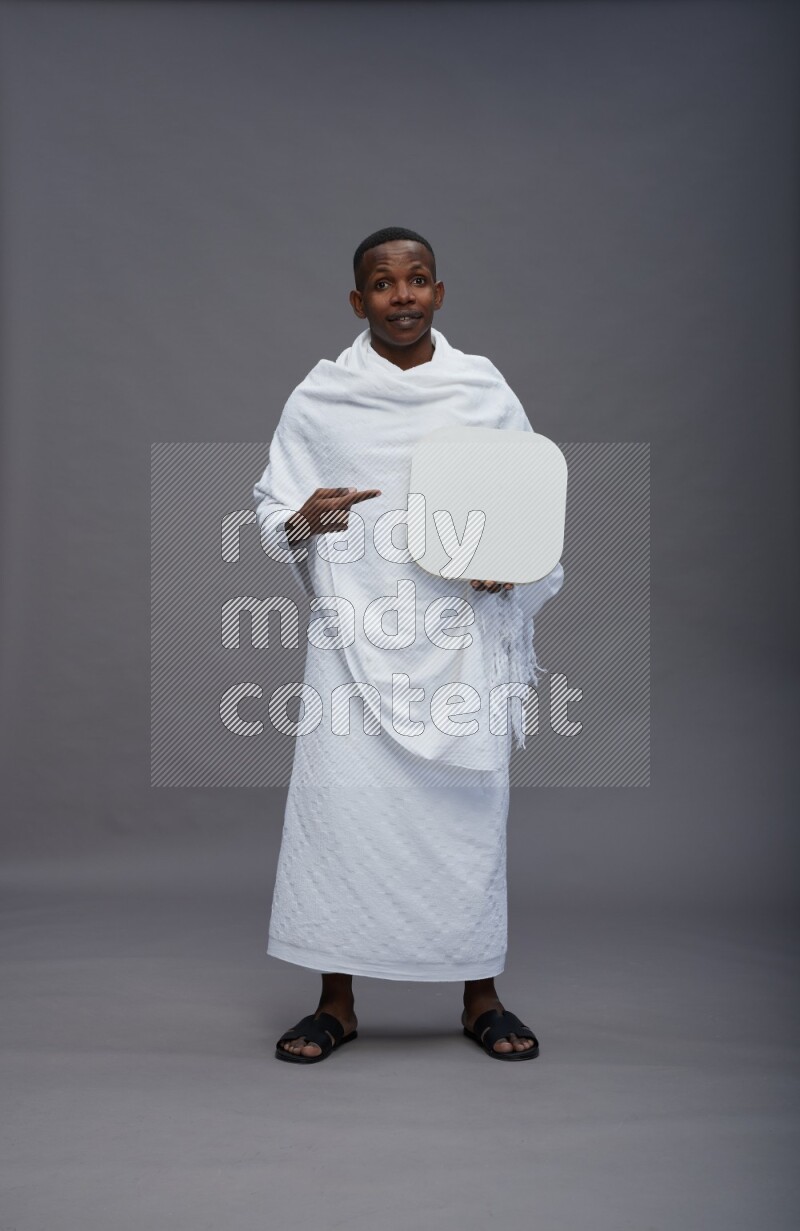 A man wearing Ehram Standing holding social media sign on gray background