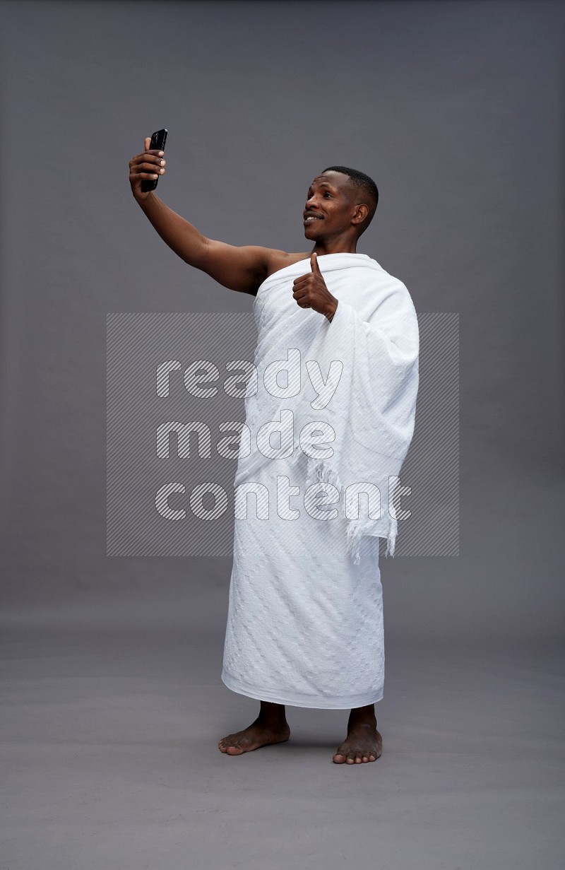 A man wearing Ehram Standing taking selfie on gray background