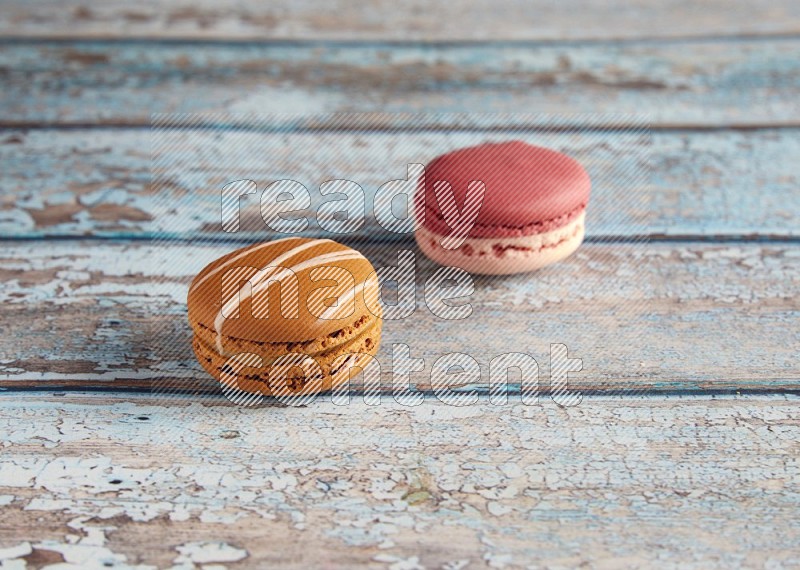 45º Shot of of two assorted Brown Irish Cream, and Pink Litchi Raspberry macarons on light blue background