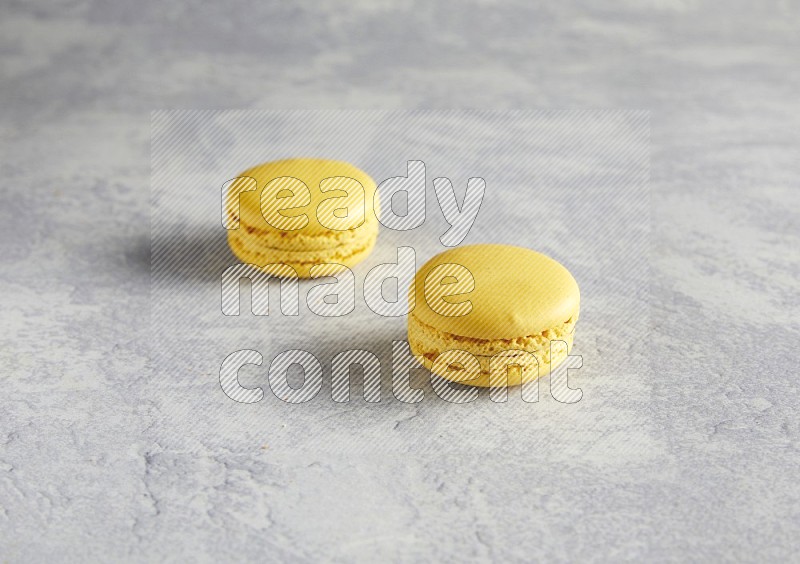 45º Shot of two Yellow Lemon macarons  on white  marble background