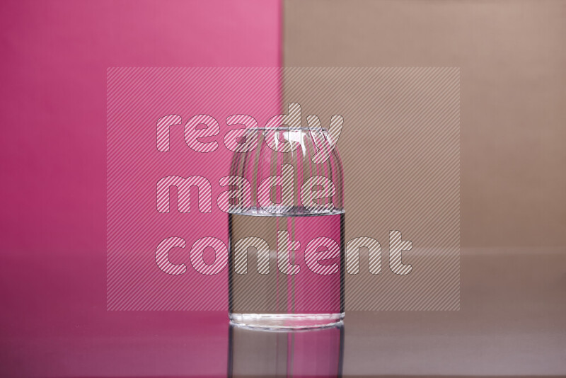 The image features a clear glassware filled with water, set against pink and beige background