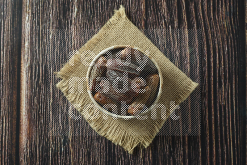 Dates in different bowls (wooden, pottery and glass) on wooden background
