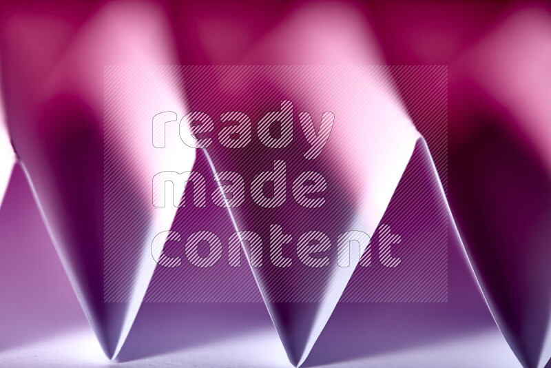 A close-up abstract image showing sharp geometric paper folds in pink gradients