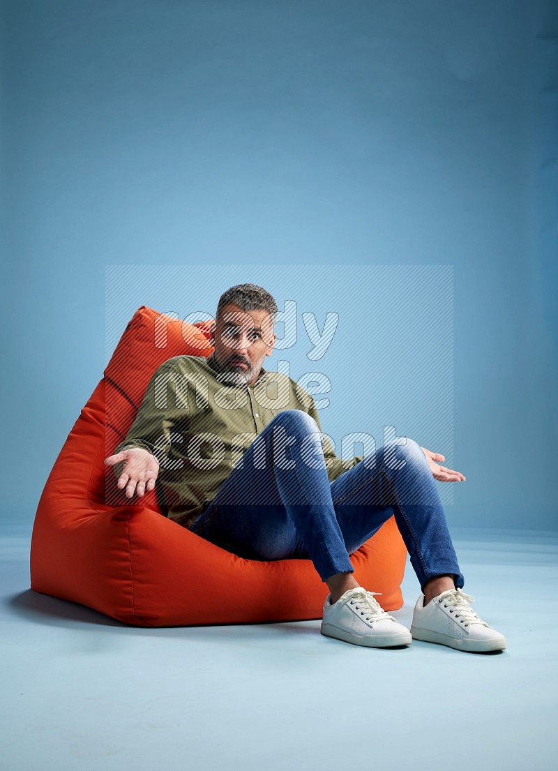A man sitting on an orange beanbag and interacting with the camera