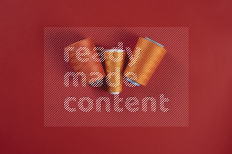 مجموعة من أدوات الخياطة والتفصيل برتقالية اللون على خلفية حمراء