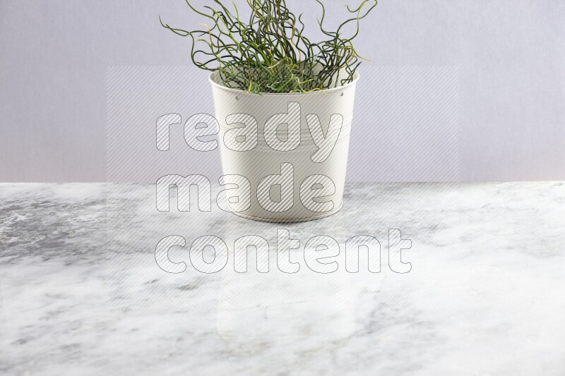 Green artificial plant in white pot on light grey marble background