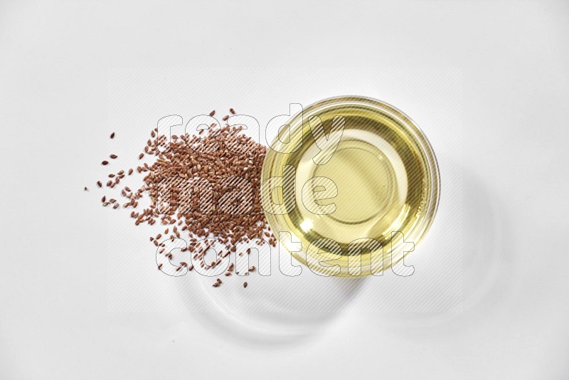 A glass bowl full of flax oil and flax seeds beside it on a white flooring in different angles