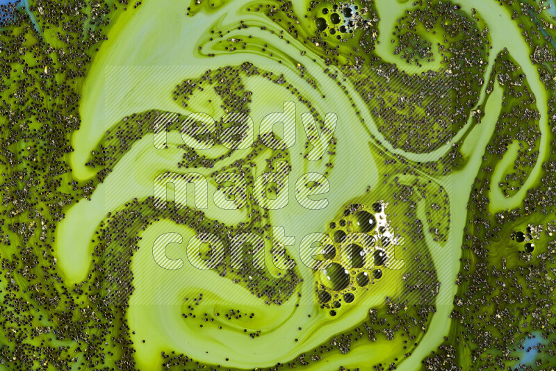 A close-up of sparkling gold glitter scattered on swirling green background