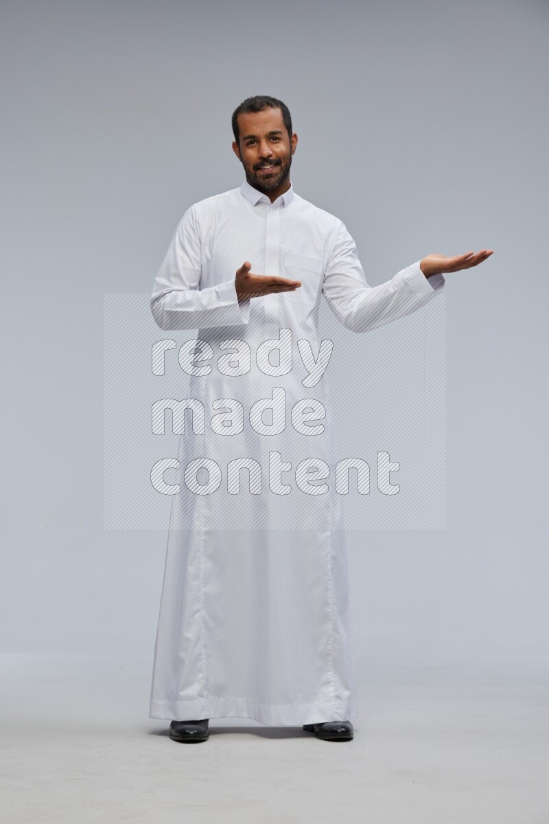 Saudi man Wearing Thob standing interacting with the camera on Gray background