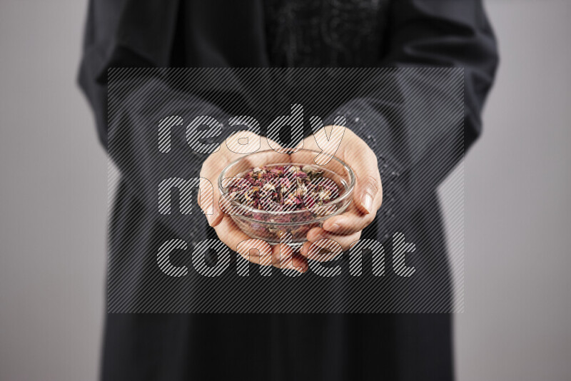 Woman in abaya holding different kinds of spices in different positions