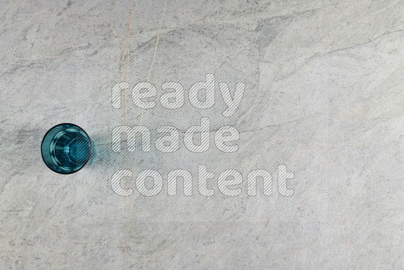 Top View Shot Of A Turquoise Glass On Grey Marble Flooring