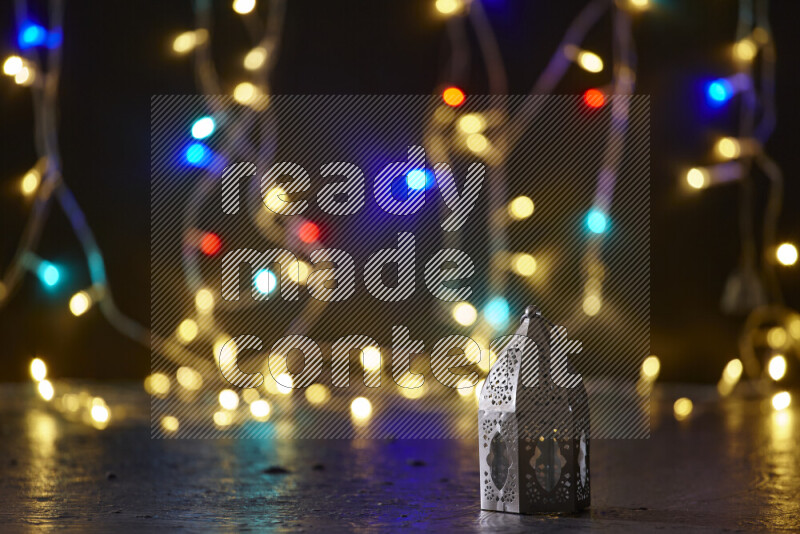 A traditional ramadan lantern surrounded by glowing fairy lights in a dark setup