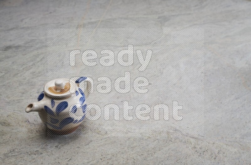 A pottery teapot on grey marble background