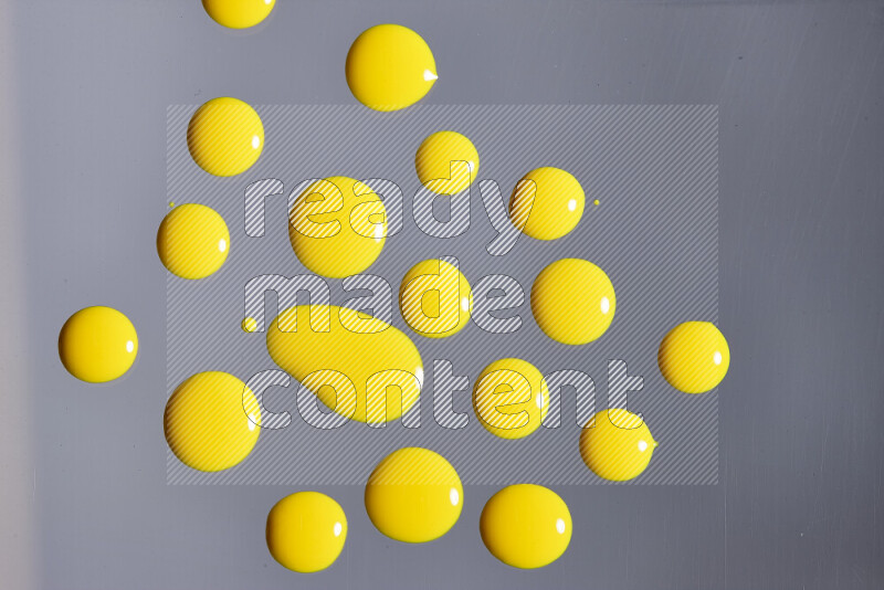 Close-ups of abstract yellow paint droplets on grey background