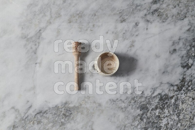 Beige pottery bowl with wooden honey dipper on the side on grey marble background