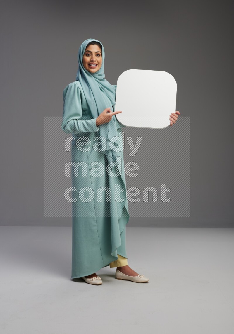 Saudi Woman wearing Abaya standing holding social media sign on Gray background