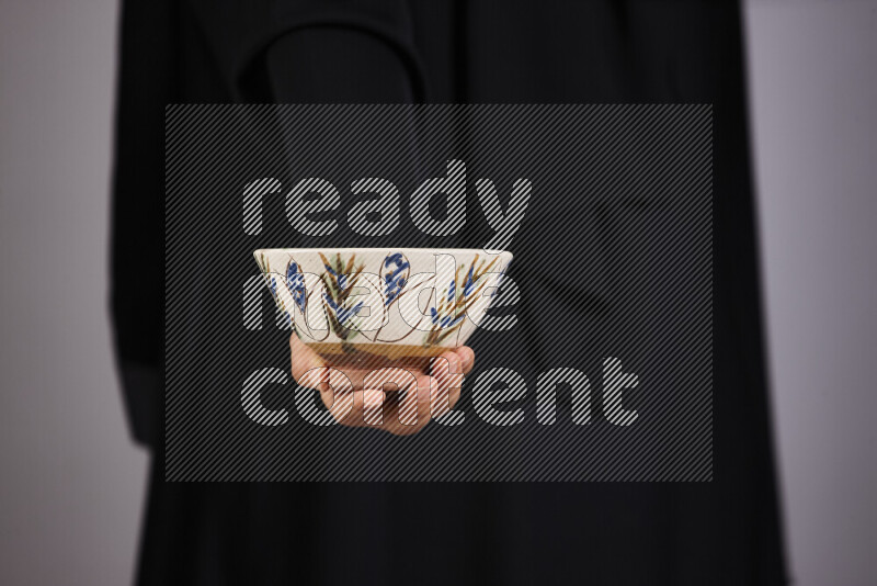 A woman in black abaya holding different pottery essentials in different positions