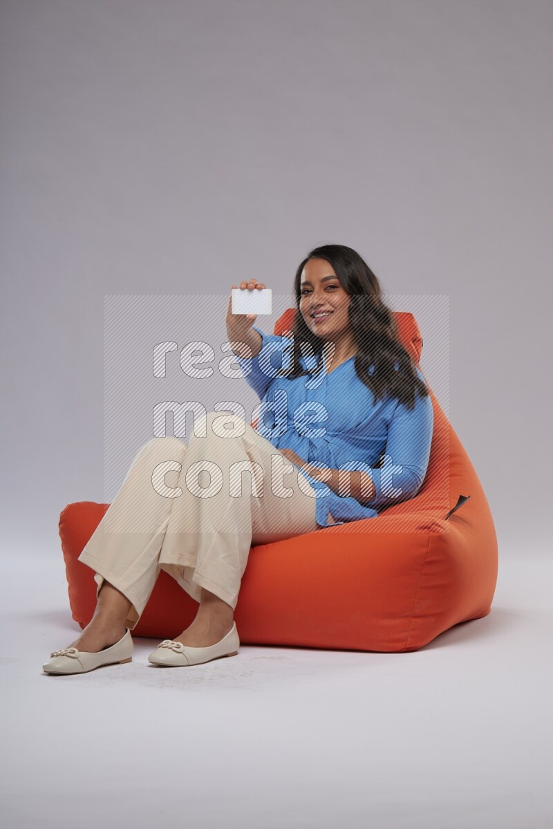 A woman sitting on an orange beanbag and holding ATM card