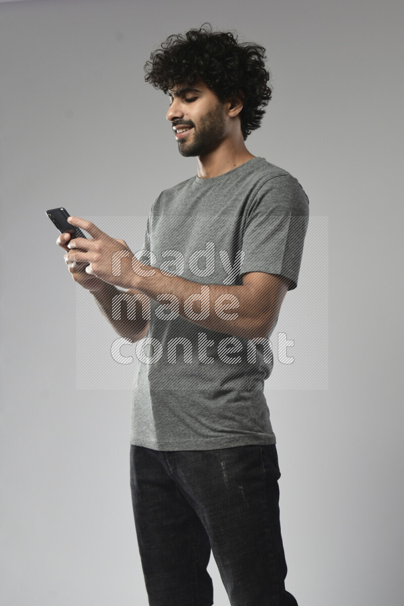 A man wearing casual standing and texting on the phone on white background
