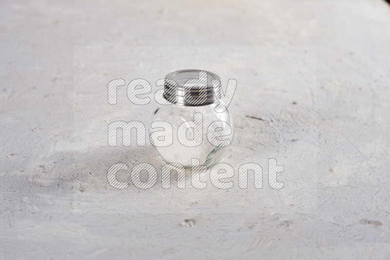 A glass jar full of coarse sea salt crystals on white background