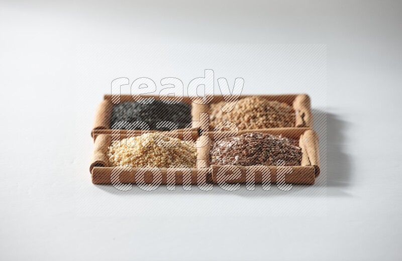4 squares of cinnamon sticks full of black seeds, mustard seeds, flaxseeds and sesame on white flooring