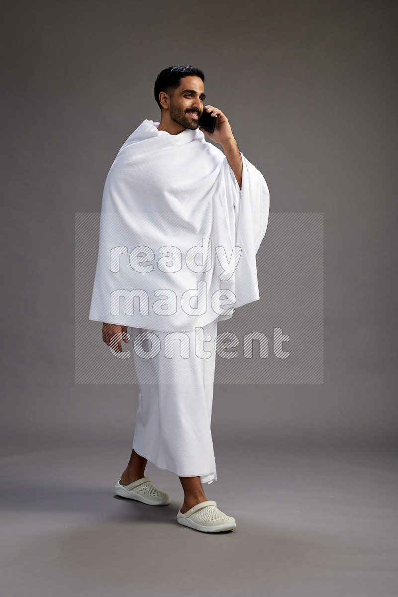 A man wearing Ehram Standing talking on phone on gray background