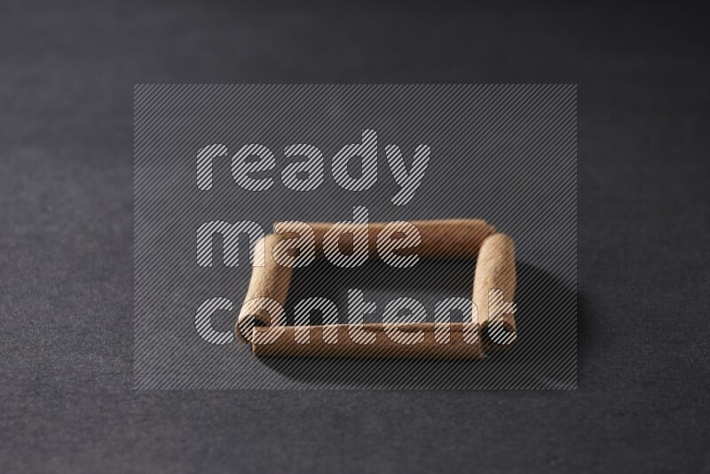 A single square of cinnamon sticks on black flooring