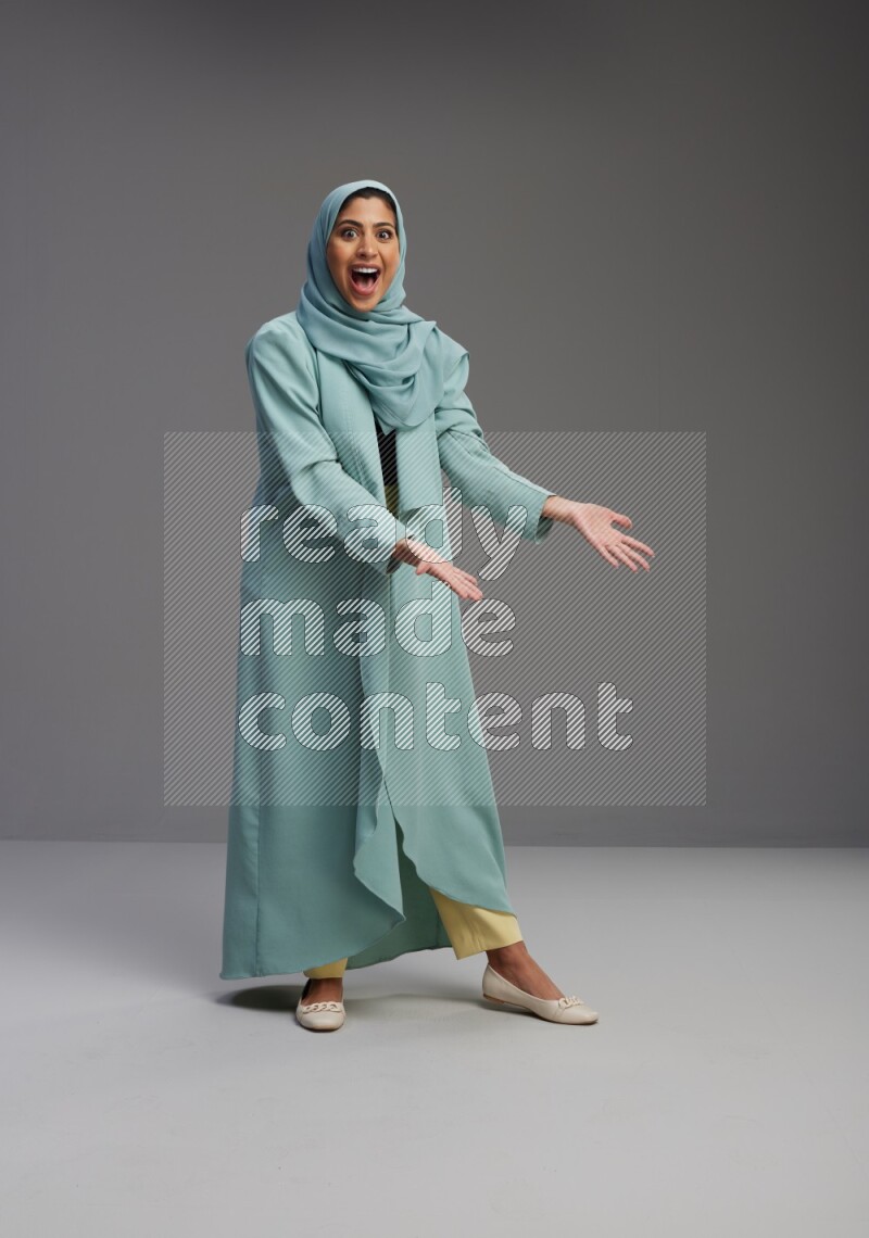 Saudi Woman wearing Abaya standing interacting with the camera on Gray background