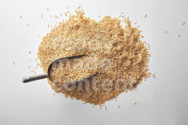 Top-view of a long grain brown rice, and shovel on white background