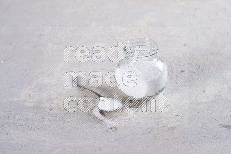 A glass jar full of fine table salt on white background