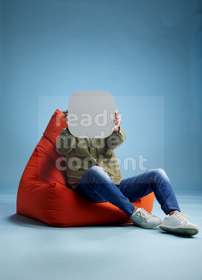 A man sitting on a orange beanbag and holding social media sign
