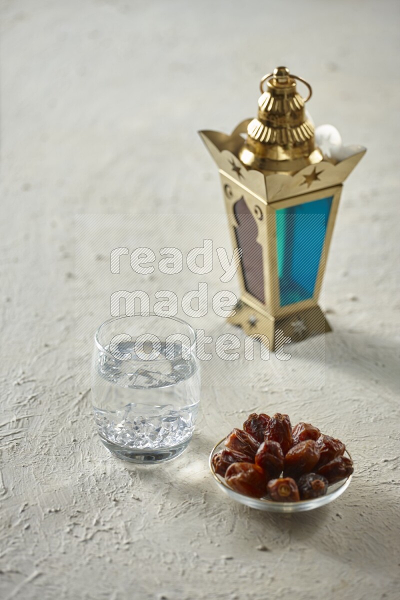 A golden lantern with different drinks, dates, nuts, prayer beads and quran on textured white background
