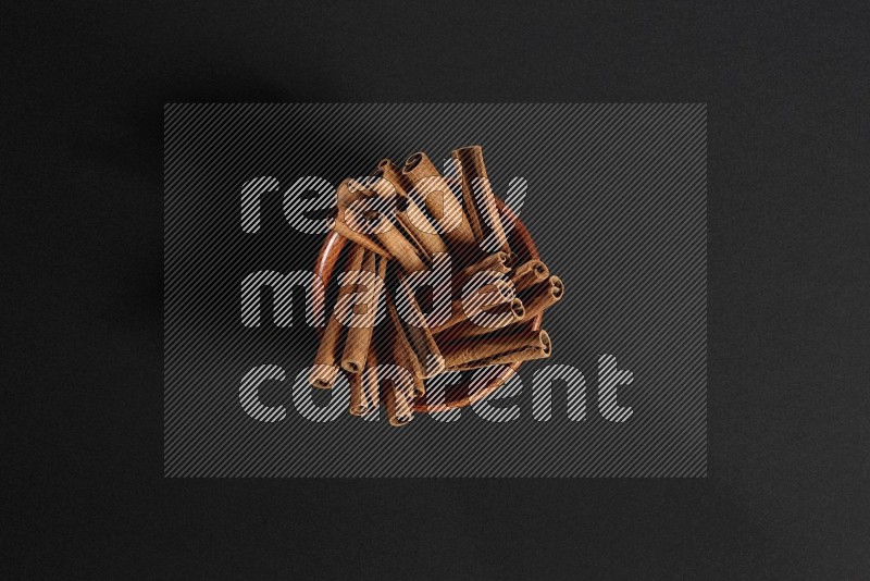 Cinnamon Sticks in a wooden bowl on black background