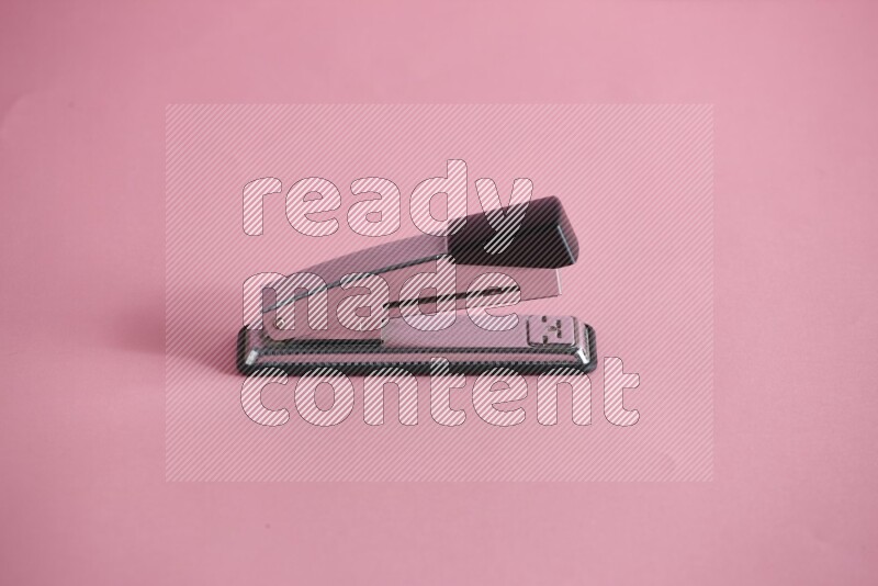 A metal stapler for paper on rose background