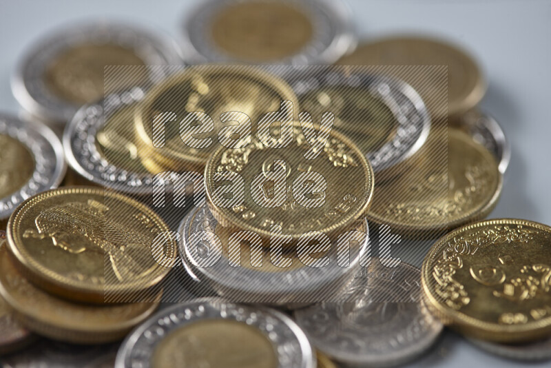 A close-up of scattered mixed Egyptian coins such as One pound, 50 and 25 piasters on grey background