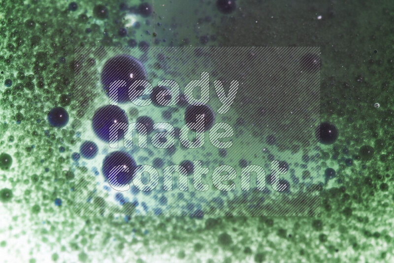 لقطات مقربة لقطرات ألوان مائية خضراء وزرقاء على سطح الزيت على خلفية بيضاء