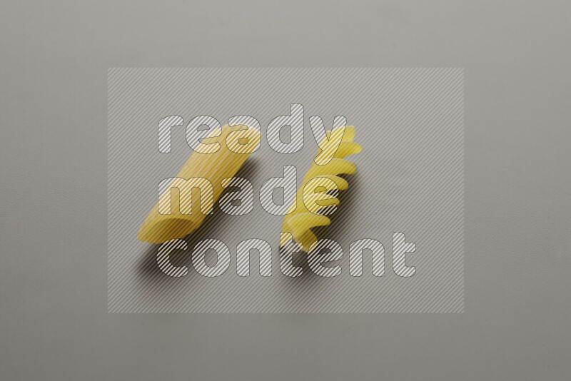 Penne pasta with other types of pasta on grey background
