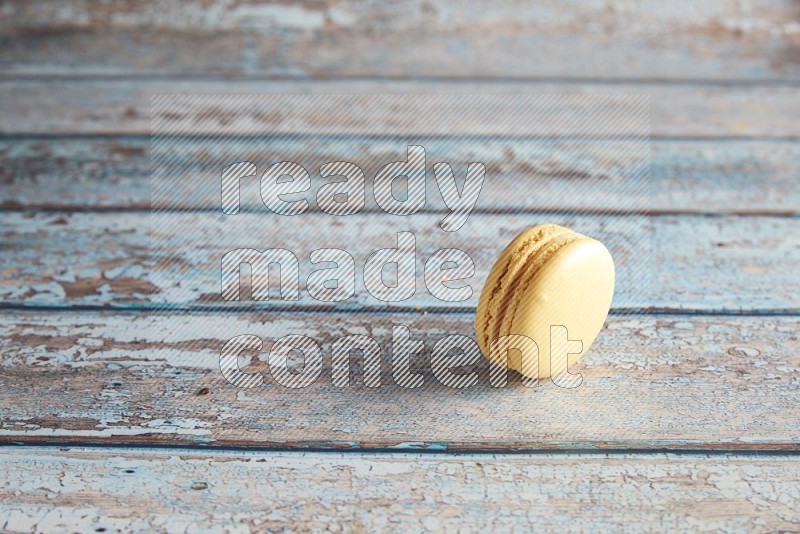 45º Shot of Yellow Vanilla macaron on light blue wooden background